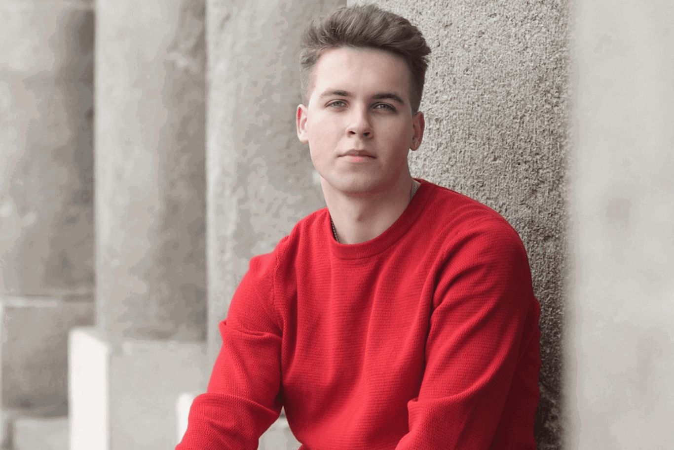 young man wearing a red sweater looking into a camera