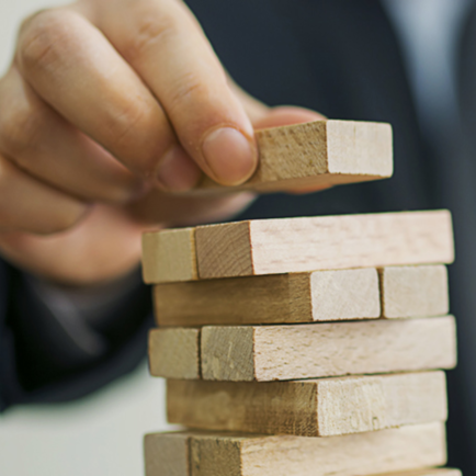 Person staking wooden tiles on top of each other, representing how we use demographic data as building blocks.